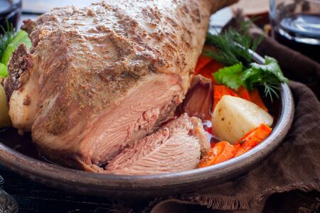 Baked turkey drumstick in a bowl, with a cut piece on a wooden table, horizontalの写真素材