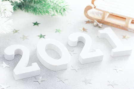 White wooden numbers for the new year on a white table with branches of a christmas tree and silver stars, symbol of the year, background, copy spaceの写真素材