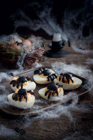 Stuffed eggs for Halloween adorned with spiders from olives, selective focusの写真素材