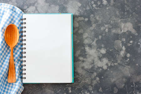 A clean culinary notebook with a blue napkin and a wooden spoon on the table, top view, copy spaceの写真素材