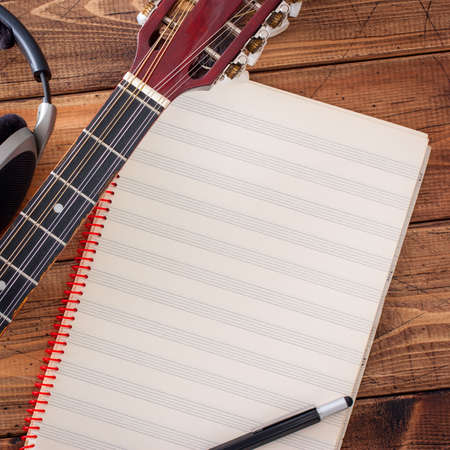 Buzuki, headphones and a clean musical note book on a wooden table, top view, musical concept, copy spaceの写真素材