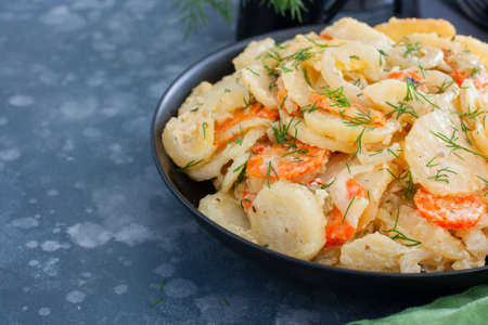 Baked potatoes with carrots in the oven on a black dish, selective focus, copy spaceの写真素材