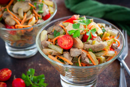 salad with chicken liver, mushrooms and tomatoes in a glass bowl, selective focusの写真素材