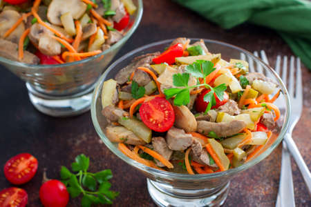 salad with chicken liver, mushrooms and tomatoes in a glass bowl, selective focusの写真素材