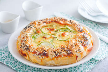Open puff pastry zucchini pie sprinkled with poppy seeds and sesame seeds, selective focusの写真素材