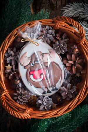 Christmas basket with cones, tree decorations and gingerbread in the form of a bull in a package, top view, selective focusの写真素材