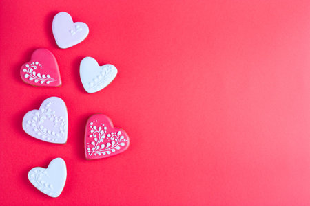 Gingerbread cookies in the form of a pink, white and red heart on a red background, valentines day,...
