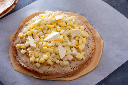 Step-by-step preparation of the festive Russian Kurnik pie, assembling a puff pie with fillings, step 5 - spreading the third filling with sliced potatoes and slices of butter on pancakes, selective focus, horizontalの写真素材