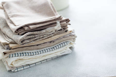 Clean kitchen textiles made of cotton and linen - napkins, towels folded on the table, horizontal, place for textの写真素材