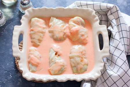 Step-by-step preparation of baked cabbage rolls, step 9 - filling the mold with raw cabbage rolls with tomato-sour cream sauce before baking, horizontalの写真素材
