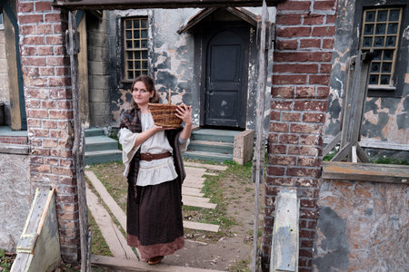 Full length portrait of a smiling girl with wicker basket. Woman in vintage linen shirt on a...