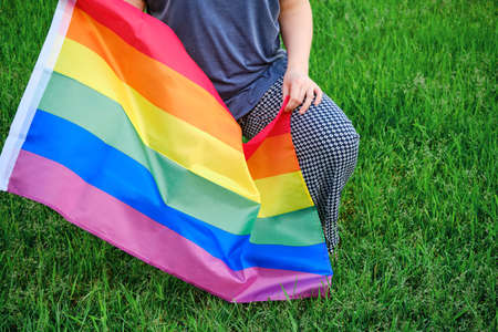 A woman knelt with a LGBT flag, background green grass in the Park. Concept of anti-racism protests and demonstrations in USAの写真素材
