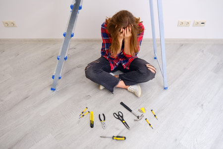 A woman in a plaid shirt crying because of trouble with the repair. Laid out construction tools in...