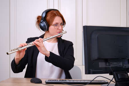 A music teacher conducts a lesson on playing a musical instrument over the Internet. Flute lessons online and online music training during quarantine for the coronavirus pandemicの写真素材