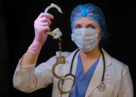 Concept of stay at home. The hands of a medic in protective gloves and medical uniforms holding handcuffed, close-up. The concept of overworking doctors during the coronavirus epidemicの写真素材
