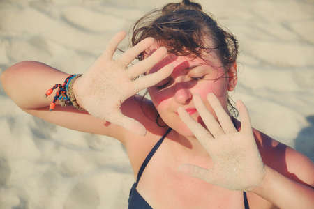 Girl put her hands in front of her face for protection from the sun.の写真素材