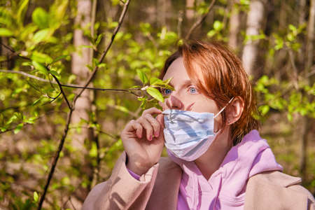 A woman near a green tree in a summer Park. Concept of the end of the flu virus epidemic, close-upの写真素材