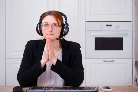 A woman prays to God at a computer during isolation due to a coronavirus. Religion and confession in online video call to the priest of the Church under quarantineの写真素材