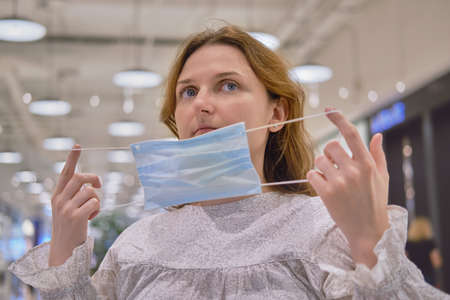 Adult woman puts on face mask on city streetの写真素材