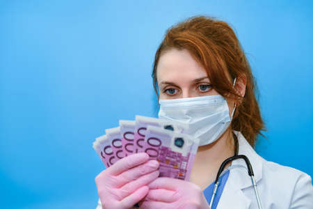Nurse counts the bills in euros, close-up. The concept of paying doctors during the coronavirus and other diseases pandemicの写真素材