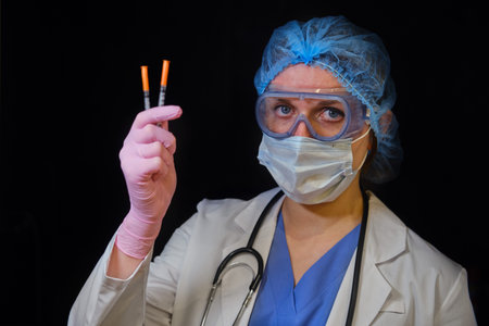 Woman doctor holds syringes in his hand on a black background, concept. Female nurse with syringes...