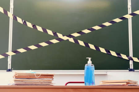 School desk with sanitizer and medical masks at the blackboard, copy spaceの写真素材