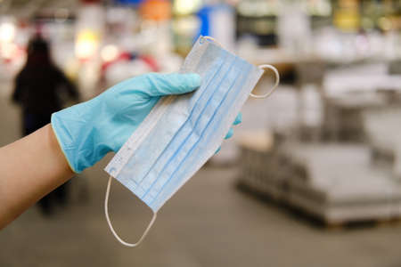 Hand in a medical glove holds a mask on the background of the store, conceptの写真素材