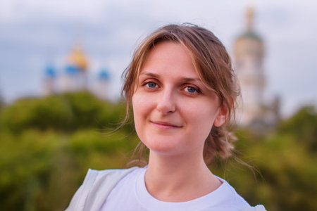Woman on the background of the Christian Church. The girl in the evening next to the domes of the temple. Female portrait on the background of the Church.の写真素材