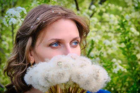 Young woman with a bouquet of fluffy white dandelionsの写真素材