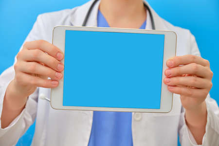 The doctor holds a digital tablet display forward, copy space for text. Nurse uses mobile Internet to help patients online, mock-up,の写真素材