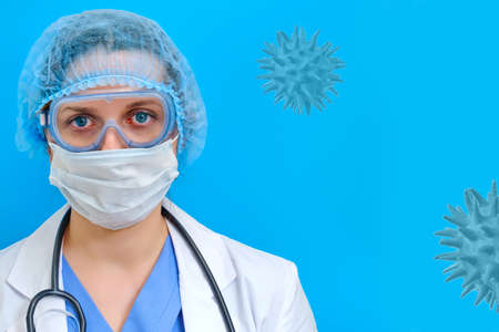 Doctor on a blue background with protective glasses on his face, copy space. Portrait of a nurse in a medical mask. Concept of fighting the coronavirus epidemic.の写真素材