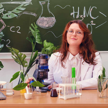 Cute woman teacher with microscope in school class at chemistry lesson. Conducting scientific research in the school laboratoryの写真素材
