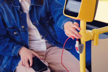 A man connects a phone wire on the bus. Mobile phone charger with usb in public transportand stop buttonの写真素材