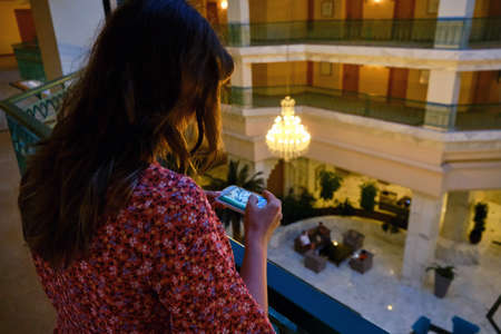 A woman takes pictures on a mobile phone in the lobby of the hotelの写真素材