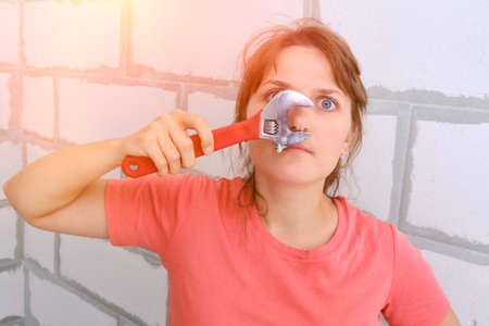 Woman twists but with a wrench. Funny girl holding a red wrench.の写真素材