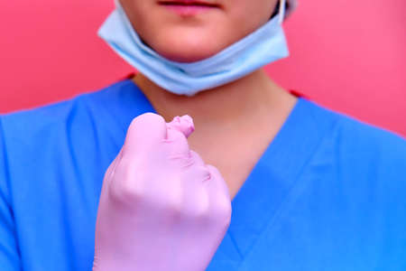Concept of stay at home. Hands of the doctor menacingly shows a fist. Close-up of a doctor in protective gloves and a medical uniformの写真素材