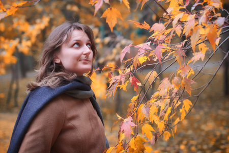 The girl looks at yellow leaves. A young woman is surprised by the arrival of autumn. The rapid...
