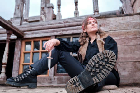 Pirate girl sitting on wooden floor with Dirk hand, selective focus on shoeの写真素材