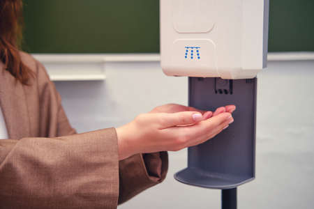 Teacher hands at the dispenser with antibacterial disinfection soapの写真素材