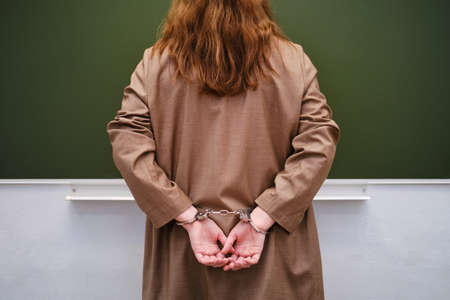 Teacher hands in handcuffs in the school classroomの写真素材