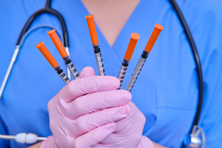 Syringes for injecting insulin in the hands of a doctor, close-up. A nurse holds syringes in pink...