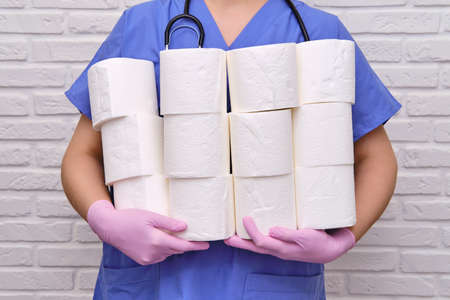 Doctor with rolls of toilet paper in his hands. A nurse holds a lot of rolls of white toilet paper, diarrhea conceptの写真素材