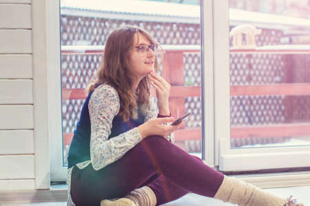 A young woman sits on a swing against the autumn landscapeの写真素材
