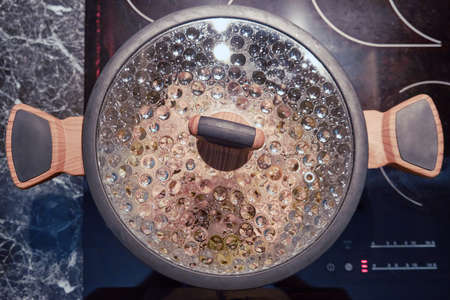 Drops on the back of the pan lid glass. Pot on the kitchen stoveの写真素材