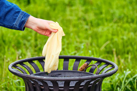 Man hand throws a medical gloves into the trash, closeup