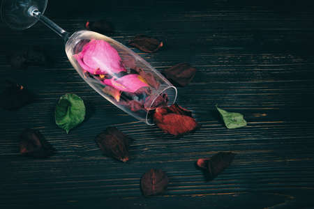 The concept of a ruined life due to alcohol problems. A wine glass filled with dead flower petalsの写真素材