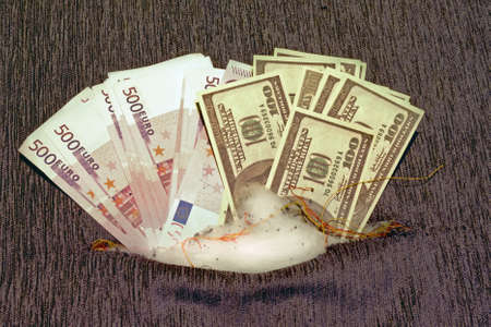Banknotes dollars and euros in the paneling of an old sofa. Cash is hidden in a pillow of old furnitureの写真素材