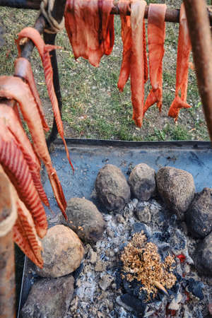 Pieces of meat dried on the fire. Stroganina is cooked on coals in the open air. Historical reconstruction of the camp of the first settlers of America, the wild West in search of gold.の写真素材