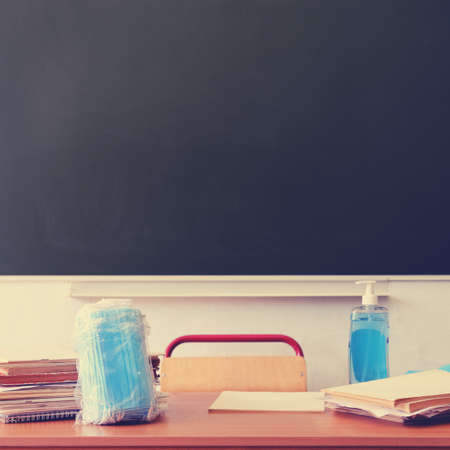 School desk with medical masks and sanitizer at the blackboard, copy spaceの写真素材