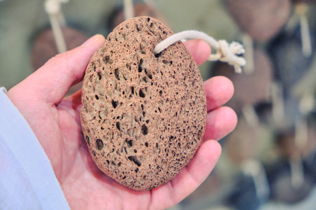 A man holding a pumice stone in his hand, close-up. Man's hand with round pumice